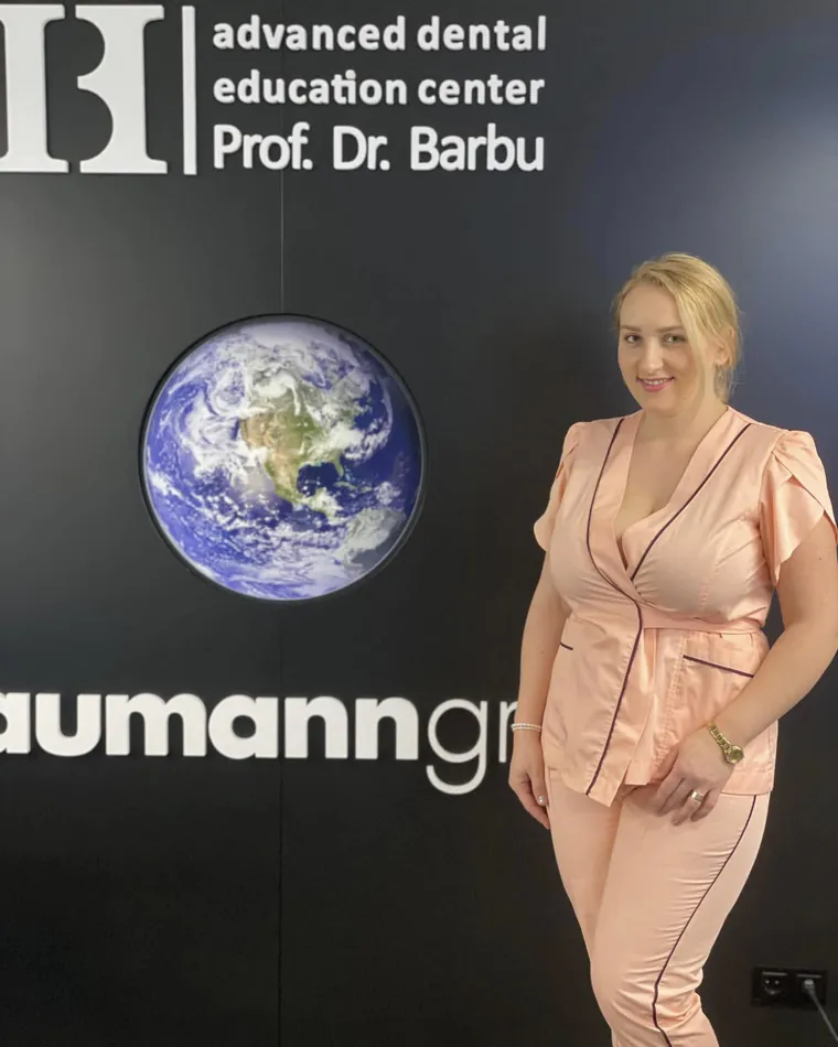 Dr. Ramona Drilea, zâmbind, în costum medical roz, la Prof. Barbu Advanced Dental Education Center